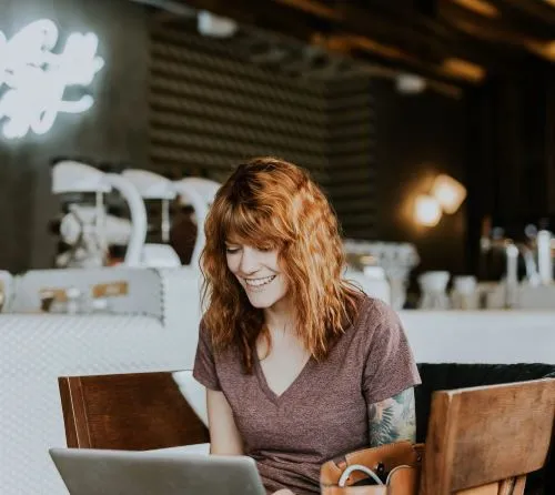 rödhårig-kvinna-med-tatuering-vid-dator