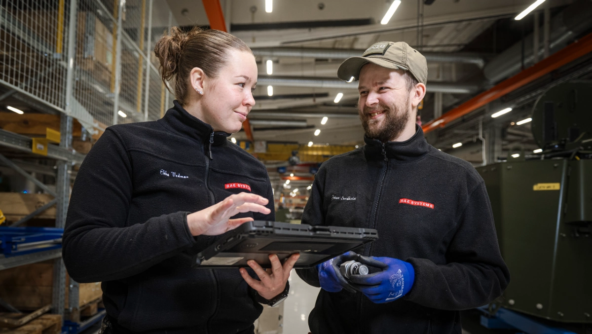 En kvinnlig och en manlig medarbetare på BAE Systems Hägglunds pratar leende med varandra