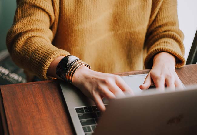 Händer på laptop, söker efter auktoriserade bemanningsbolag, som Manpower.